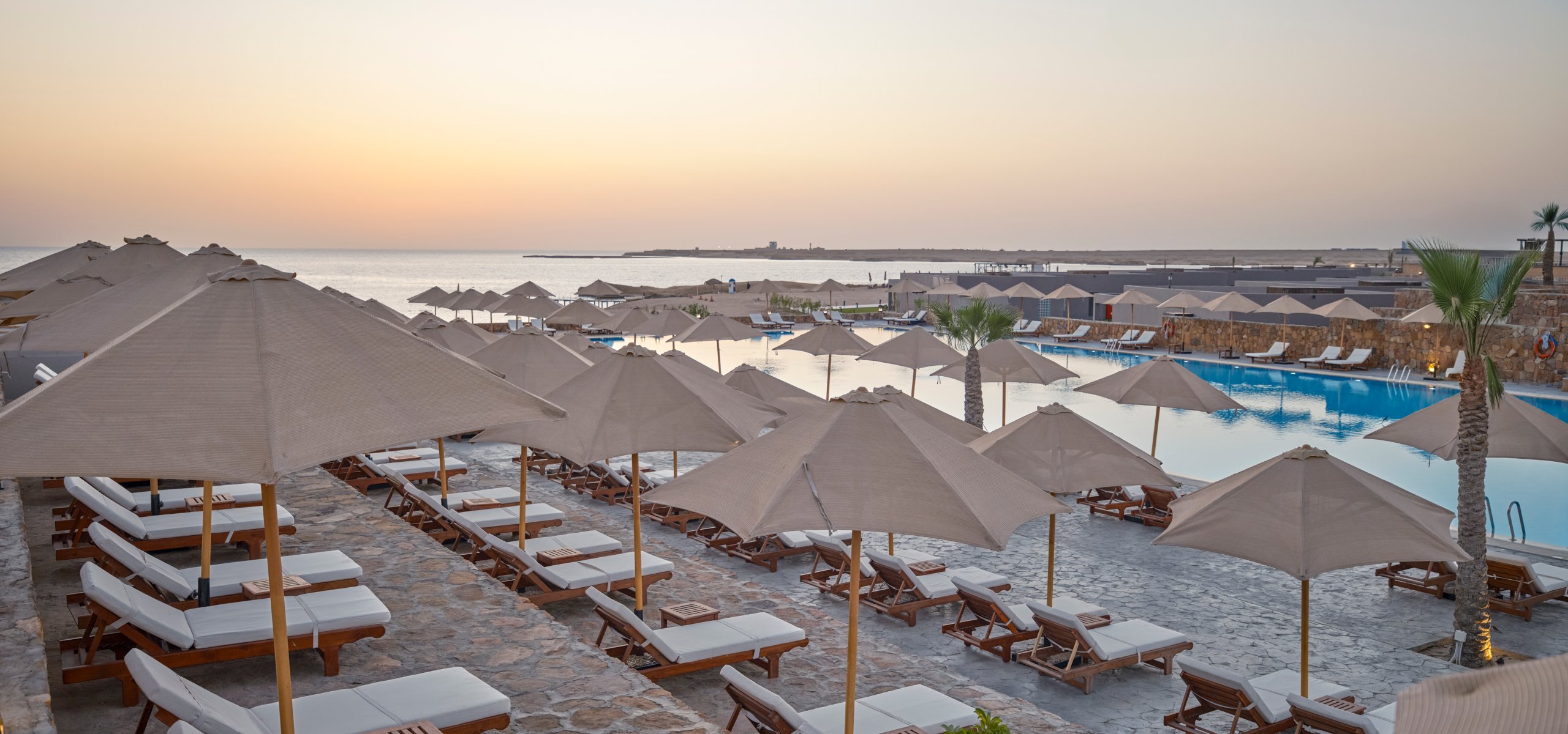 Aldiana Club Naga Bay · Strandhotel mit Sonnenschirmen, Liegen und Blick aufs Meer bei Aldiana, Urlaubsatmosphäre.