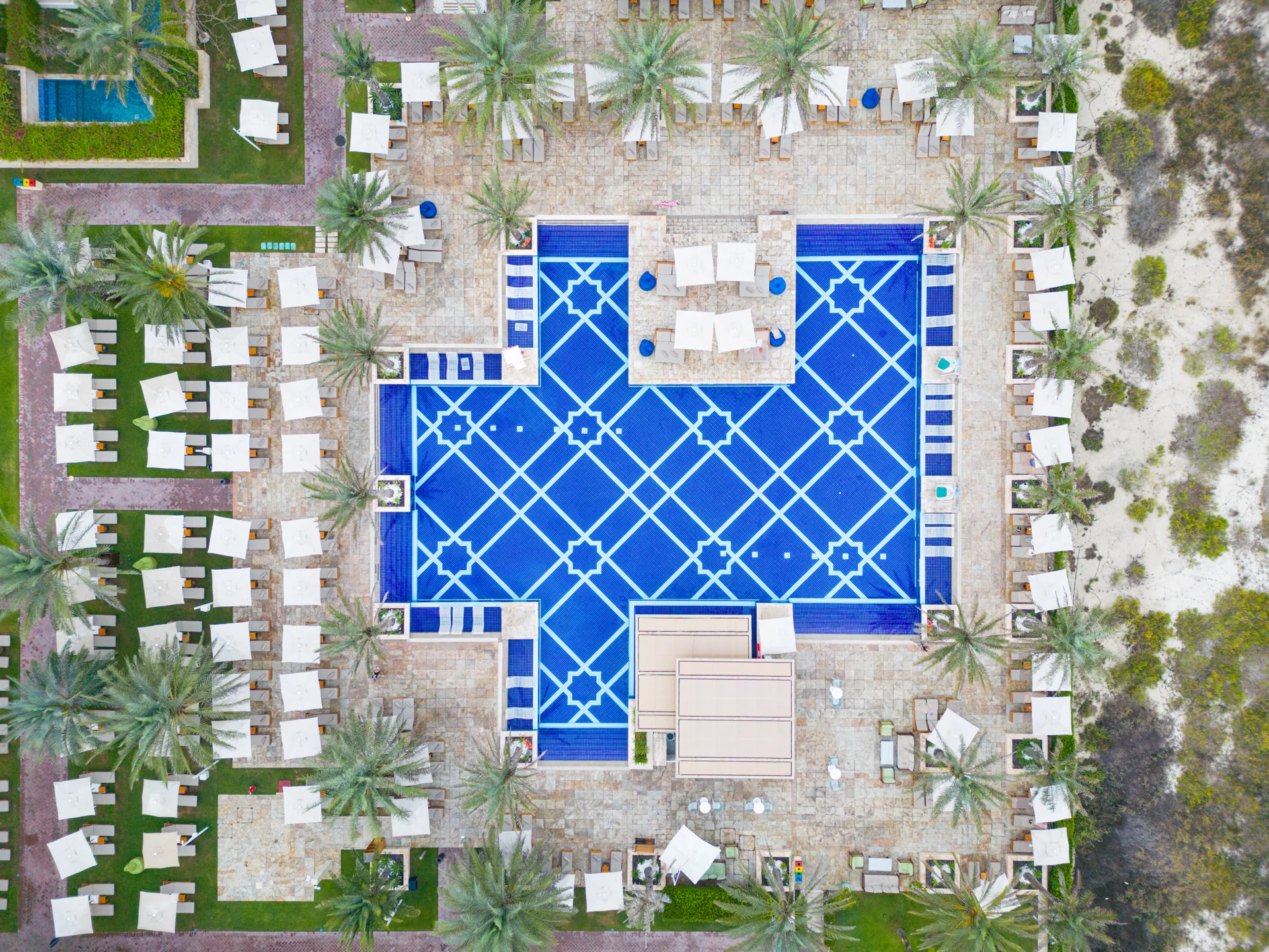 Rixos Premium Saadiyat Island · Topshot des Pools mit Sonnenliegen und Palmen