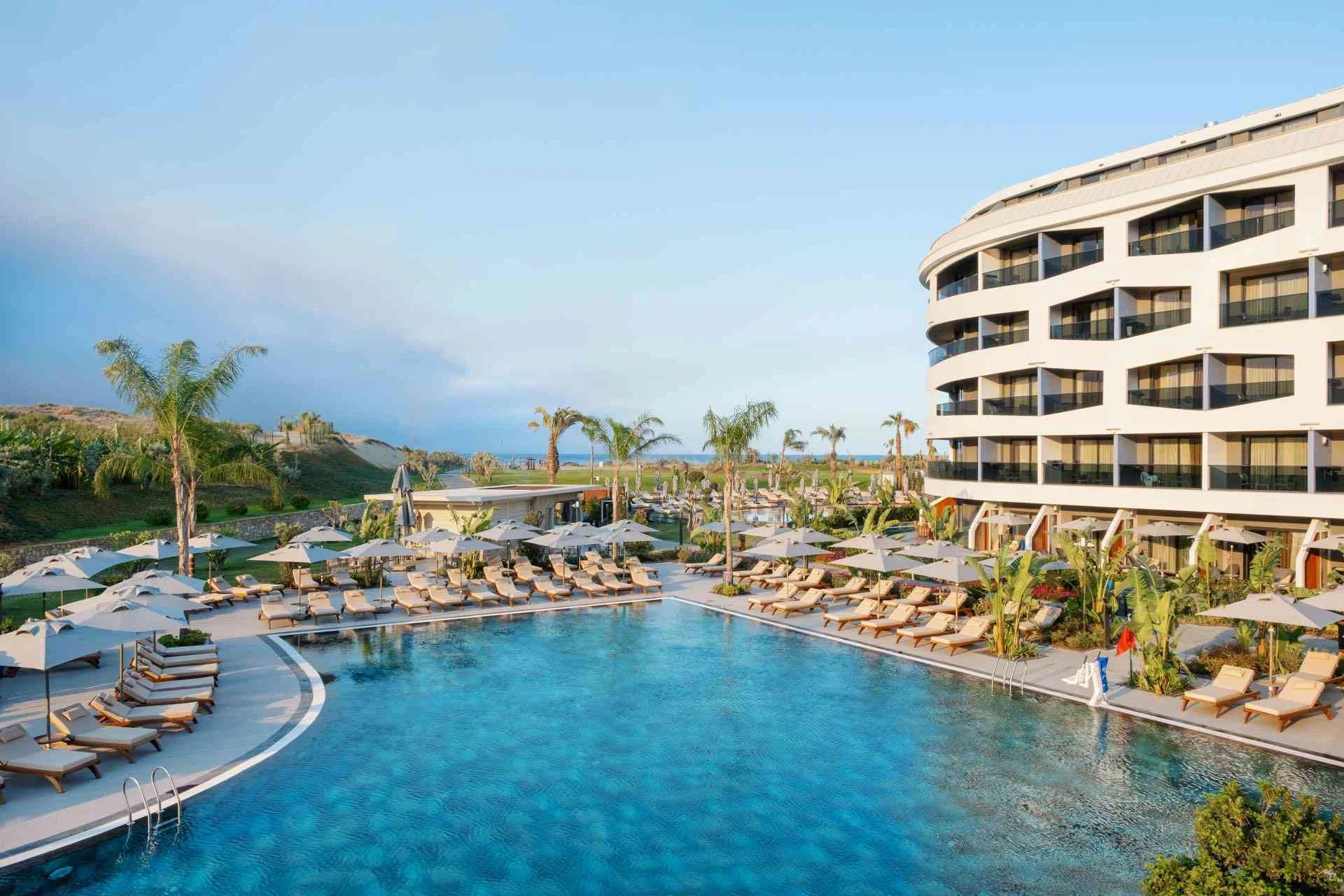 LIU Resorts · Moderner Hotelpool mit Sonnenliegen und Palmen unter blauem Himmel.